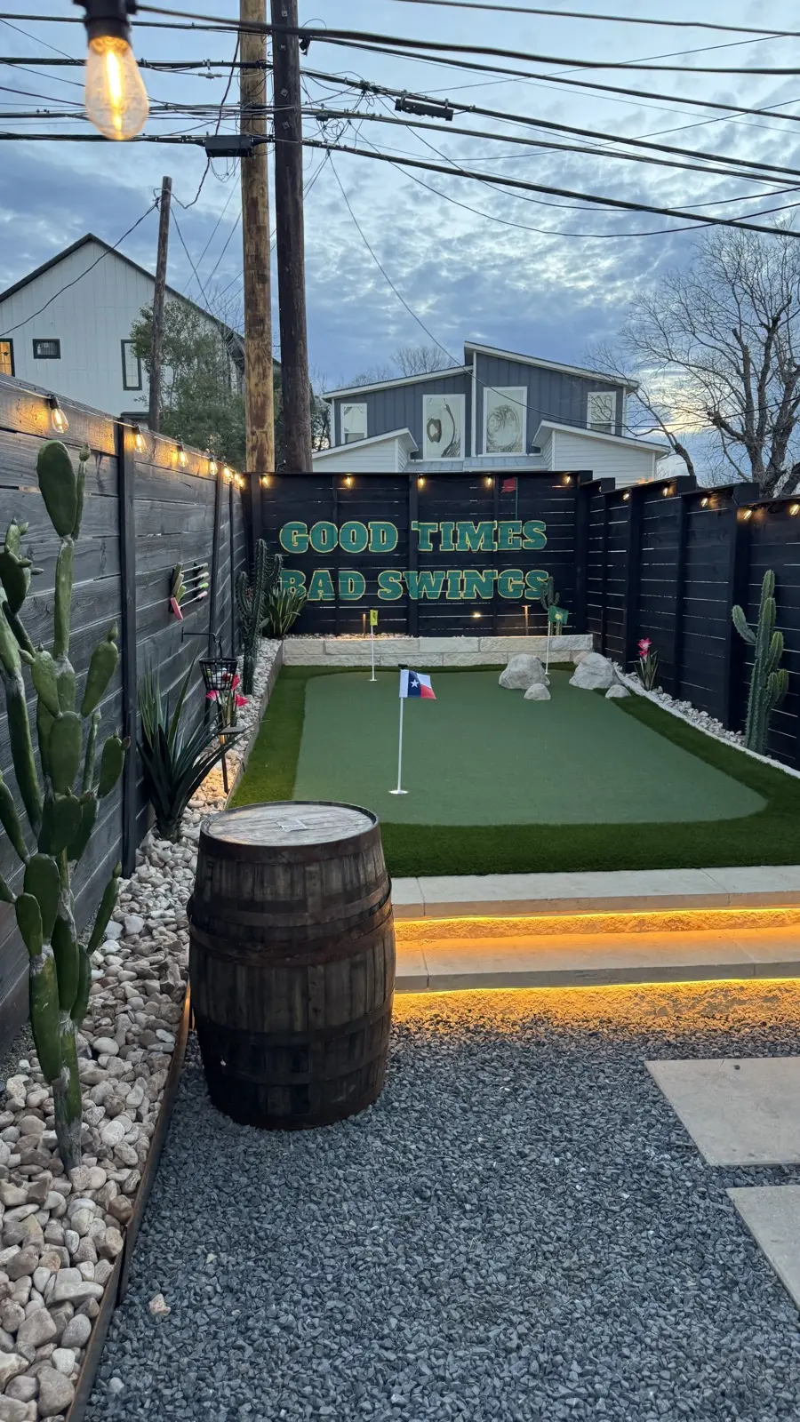The backyard putting green at night with string lights and lit limestone steps