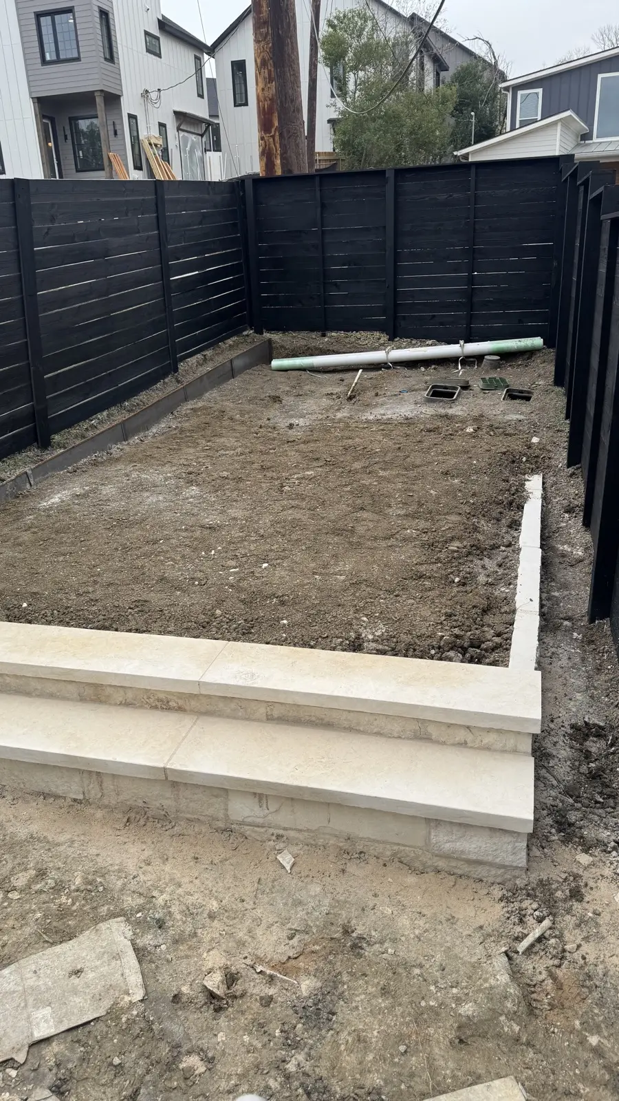 Excavated Airbnb backyard with new limestone steps being formed during turf install